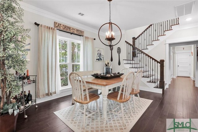 dining area featuring dark wood-type flooring, a notable chandelier, and ornamental molding