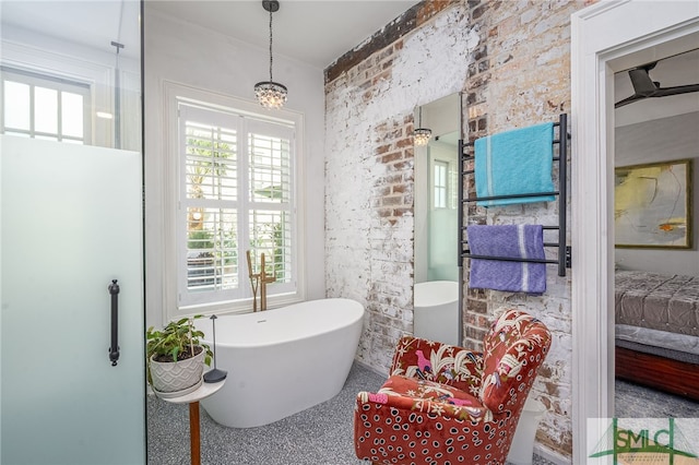 bathroom with a bath, a notable chandelier, and brick wall