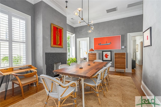 dining area featuring wood-type flooring, plenty of natural light, and ornamental molding