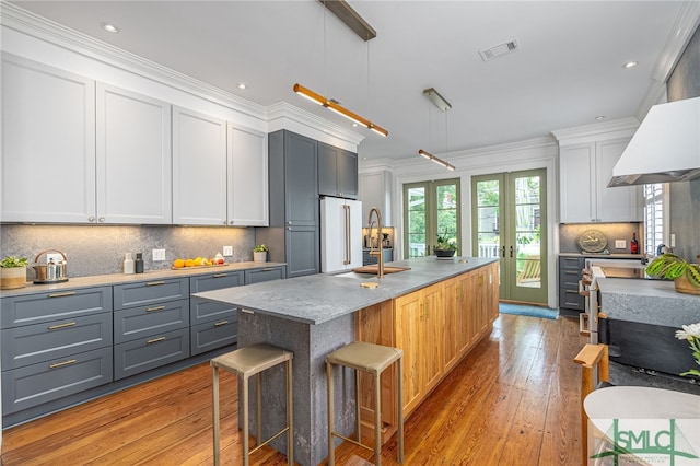 kitchen featuring a kitchen bar, decorative light fixtures, crown molding, and gray cabinetry