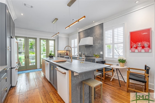 kitchen featuring appliances with stainless steel finishes, decorative light fixtures, a kitchen island with sink, and gray cabinetry