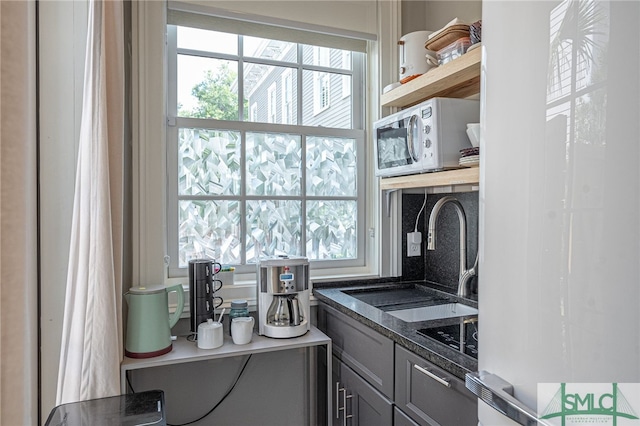 kitchen with white appliances, dark stone countertops, and sink