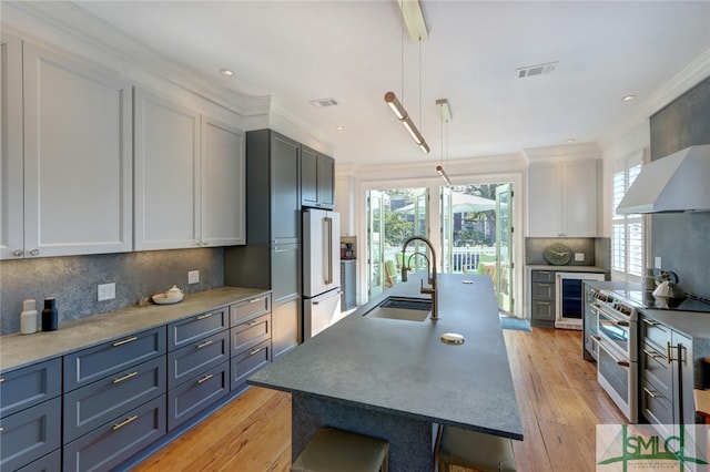 kitchen with backsplash, premium appliances, sink, and hanging light fixtures