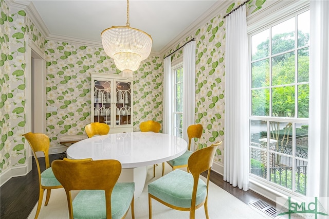 dining room with a healthy amount of sunlight, dark hardwood / wood-style floors, an inviting chandelier, and crown molding