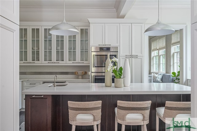 kitchen featuring white cabinets, sink, decorative light fixtures, a kitchen bar, and stainless steel double oven