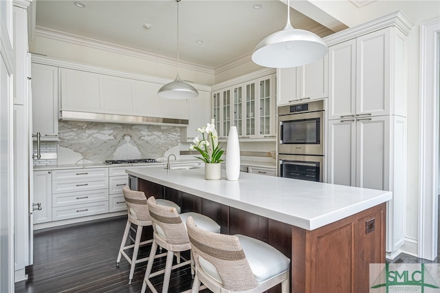 kitchen featuring a kitchen breakfast bar, tasteful backsplash, white cabinetry, and an island with sink