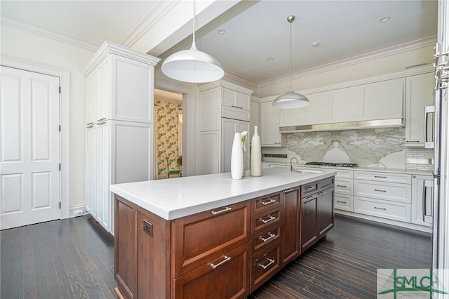 kitchen with pendant lighting, decorative backsplash, a center island with sink, and ornamental molding