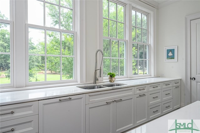 kitchen featuring white cabinets, light stone counters, and sink