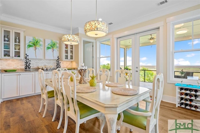 dining area featuring dark wood-type flooring, ornamental molding, and french doors