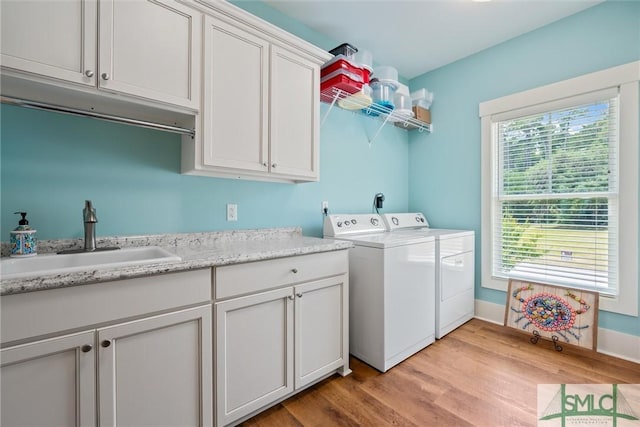 washroom featuring cabinets, light hardwood / wood-style floors, sink, and washer and dryer