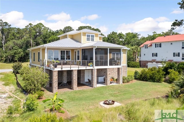 back of property with a fire pit, a lawn, and a sunroom