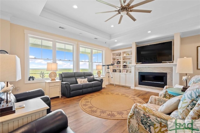 living room with ornamental molding, light hardwood / wood-style flooring, and a tray ceiling