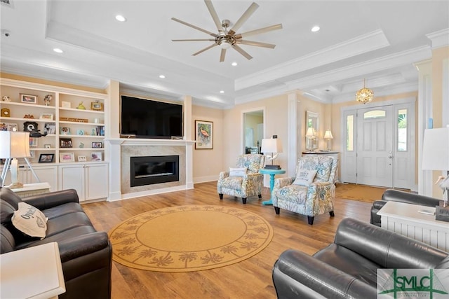 living room featuring ornamental molding, light hardwood / wood-style floors, a raised ceiling, and ceiling fan