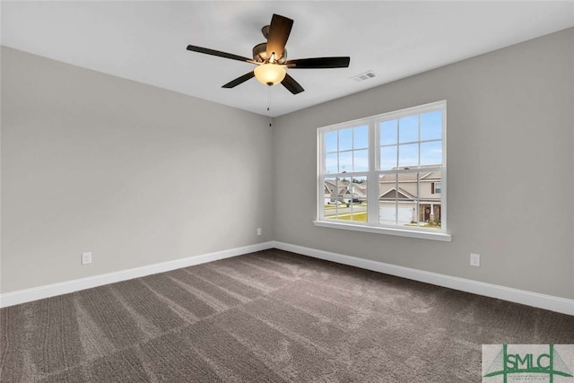 empty room featuring ceiling fan and dark colored carpet