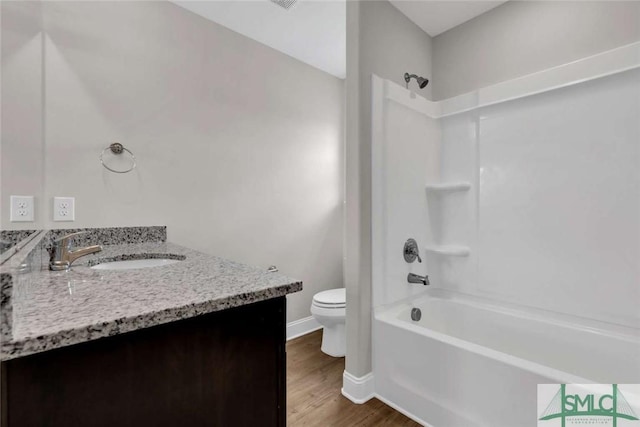 full bath with toilet, vanity, shower / tub combination, wood finished floors, and baseboards