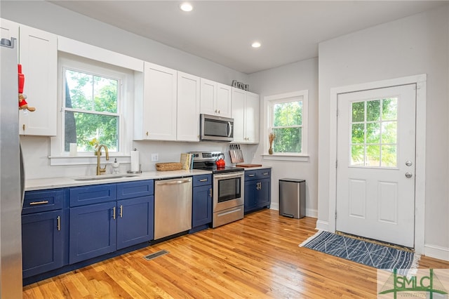 kitchen with light hardwood / wood-style floors, white cabinetry, sink, and appliances with stainless steel finishes