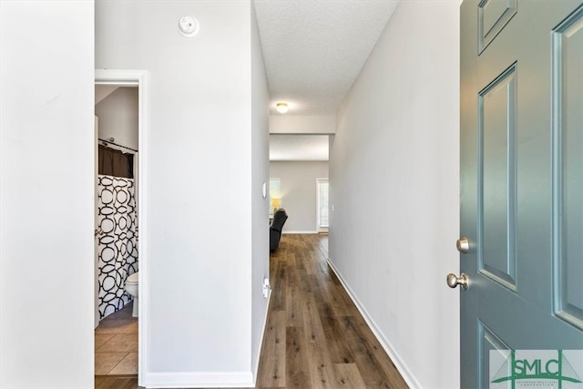 hallway with a textured ceiling and dark hardwood / wood-style floors