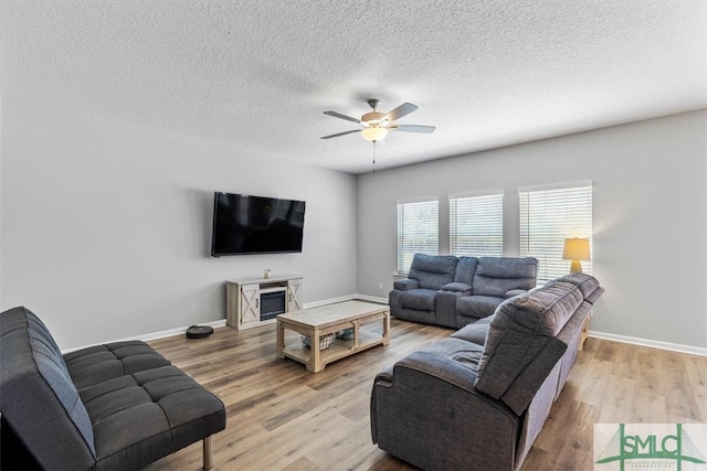 living room with a textured ceiling, ceiling fan, and light hardwood / wood-style flooring