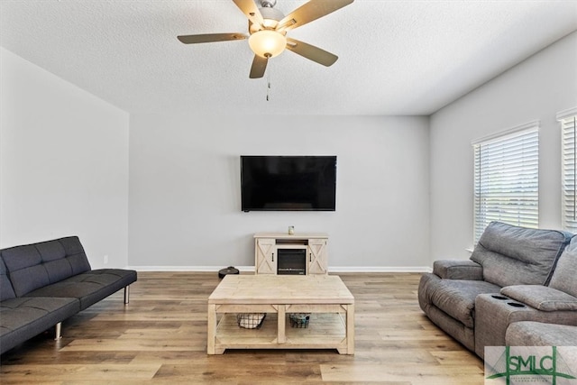 living room featuring hardwood / wood-style flooring, ceiling fan, and a textured ceiling