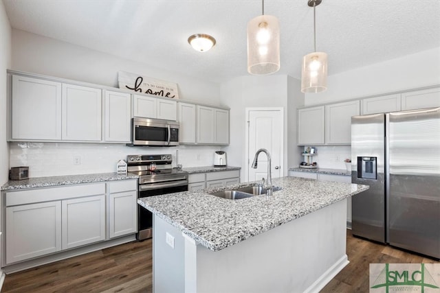 kitchen with appliances with stainless steel finishes, sink, an island with sink, and dark hardwood / wood-style flooring