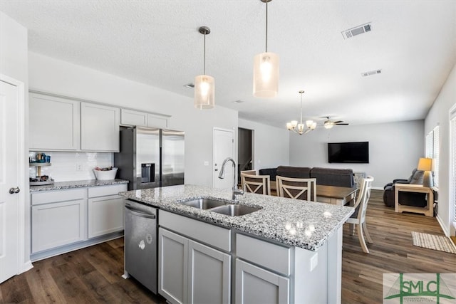 kitchen with appliances with stainless steel finishes, sink, dark wood-type flooring, and a kitchen island with sink