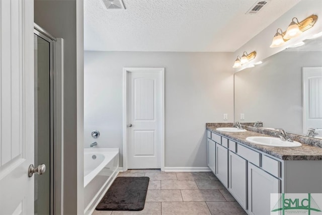 bathroom with a bath, tile flooring, double sink vanity, and a textured ceiling