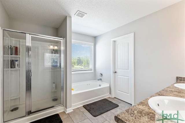 bathroom featuring dual vanity, tile flooring, a textured ceiling, and plus walk in shower