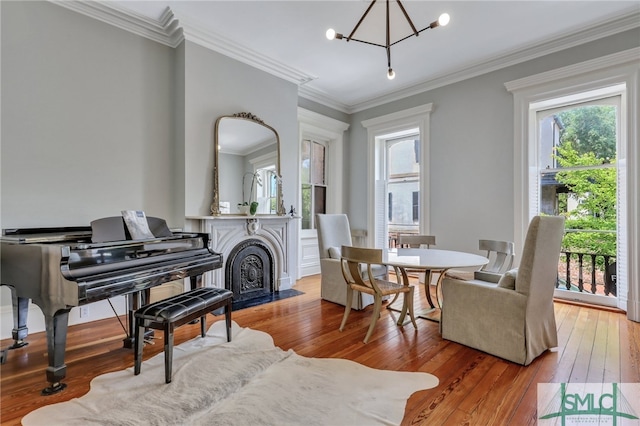 sitting room featuring hardwood / wood-style floors, ornamental molding, and a notable chandelier