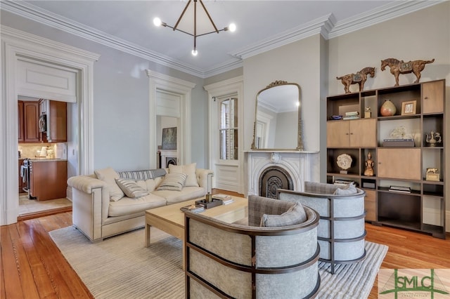 living room with light wood-type flooring, ornamental molding, and an inviting chandelier