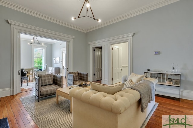 living room with wood-type flooring, an inviting chandelier, and crown molding