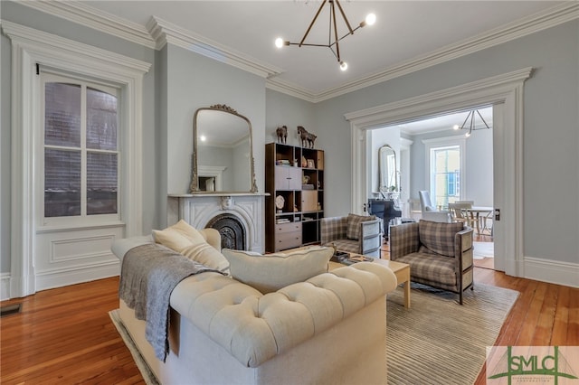 living room with ornamental molding, a chandelier, and light hardwood / wood-style floors