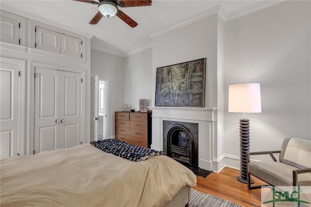 bedroom with ceiling fan, a closet, light hardwood / wood-style floors, and crown molding