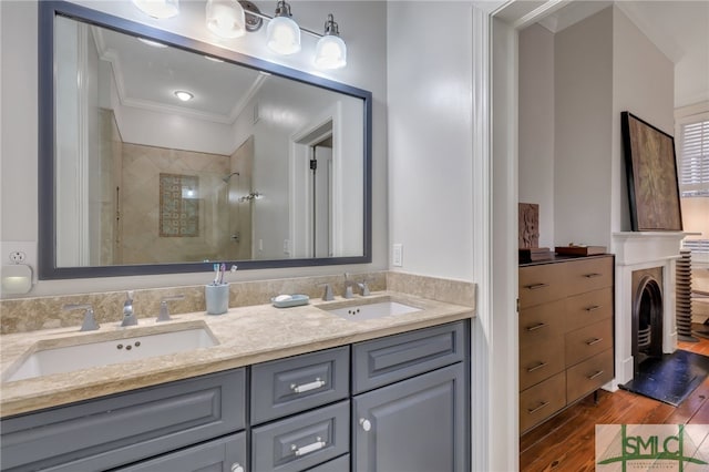 bathroom featuring crown molding, hardwood / wood-style flooring, double vanity, and a shower