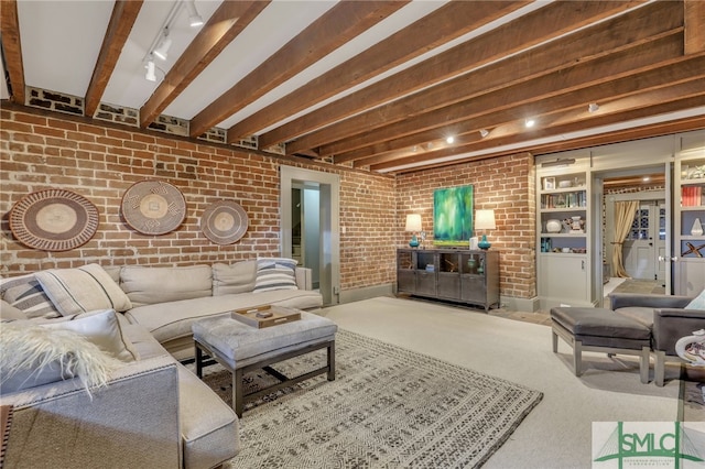 living room with beam ceiling, track lighting, brick wall, and carpet floors