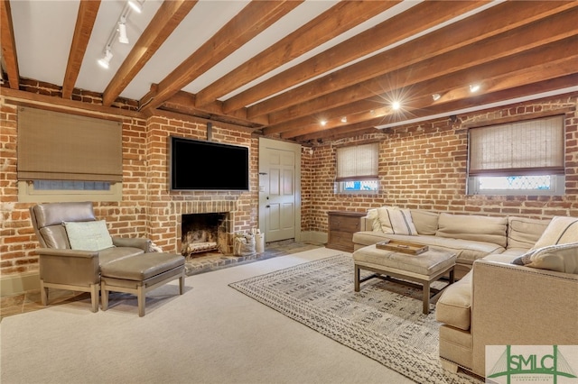 living room with a brick fireplace, carpet floors, rail lighting, beamed ceiling, and brick wall