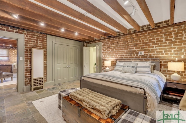 tiled bedroom with beam ceiling, brick wall, and a closet