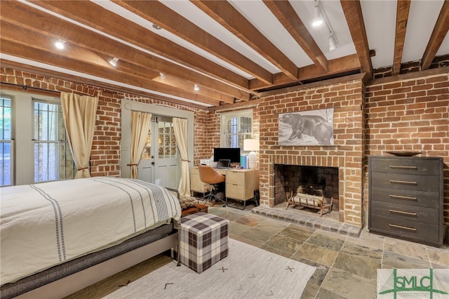 tiled bedroom with brick wall, beamed ceiling, and a brick fireplace