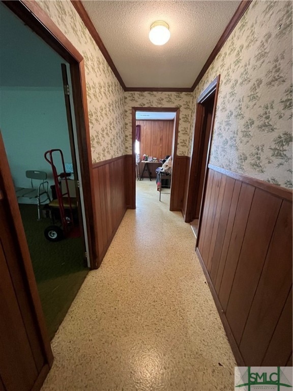 corridor featuring a textured ceiling and crown molding