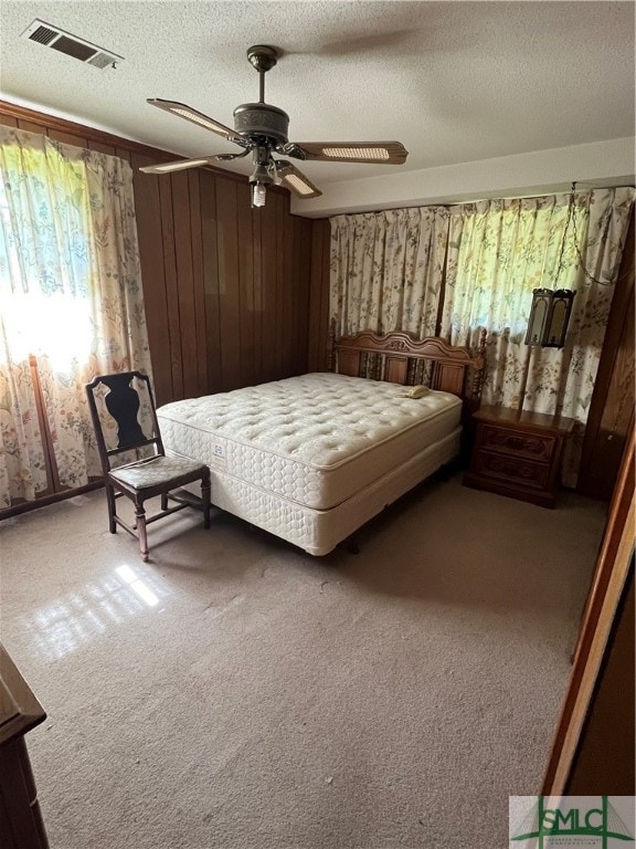 bedroom featuring carpet flooring, ceiling fan, a textured ceiling, and wood walls