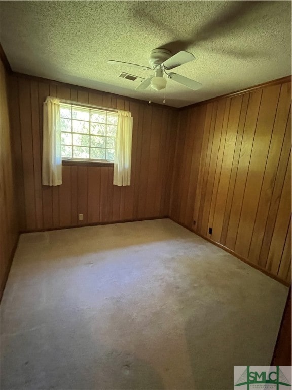 carpeted empty room featuring wood walls and a textured ceiling