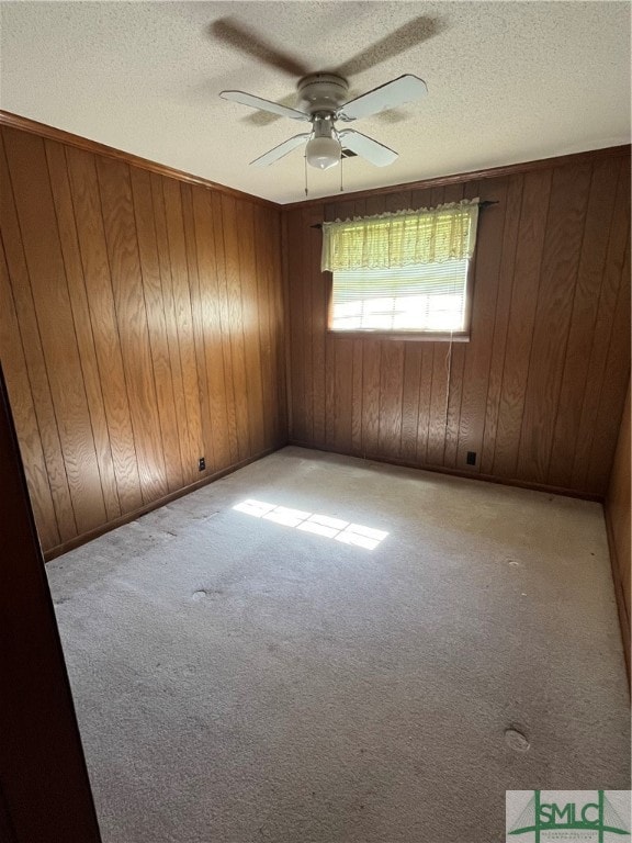 spare room with ceiling fan, wood walls, and light carpet