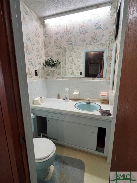 bathroom featuring tile walls, vanity, a textured ceiling, and toilet