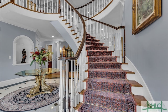 stairs featuring ornate columns, a towering ceiling, and crown molding