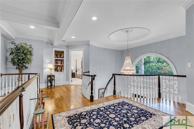 hallway featuring beamed ceiling, hardwood / wood-style floors, ornamental molding, and built in shelves