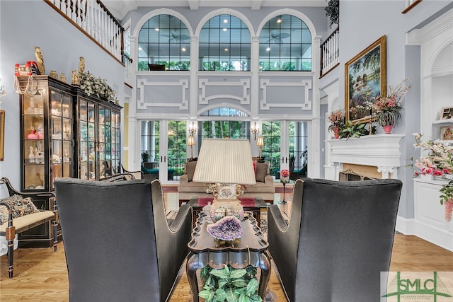 living room with a healthy amount of sunlight, french doors, light hardwood / wood-style floors, and a high ceiling