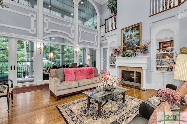 living room with a wealth of natural light, wood-type flooring, and a high end fireplace