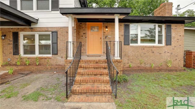 property entrance with brick siding and a chimney