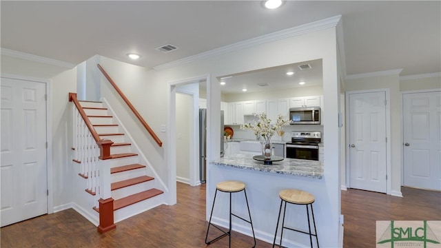 kitchen with visible vents, dark wood-style floors, a breakfast bar, stainless steel appliances, and white cabinetry