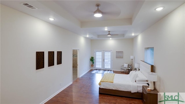 bedroom with wood finished floors, visible vents, baseboards, french doors, and a tray ceiling