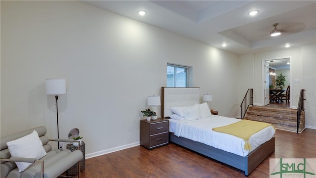 bedroom with baseboards, a raised ceiling, dark wood-type flooring, and recessed lighting